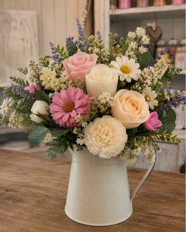 A beautiful handcrafted bouquet of roses, gerberas and wildflowers in a rustic white jug